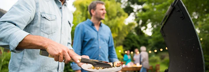 Person grillt Fleisch mit Grillzange